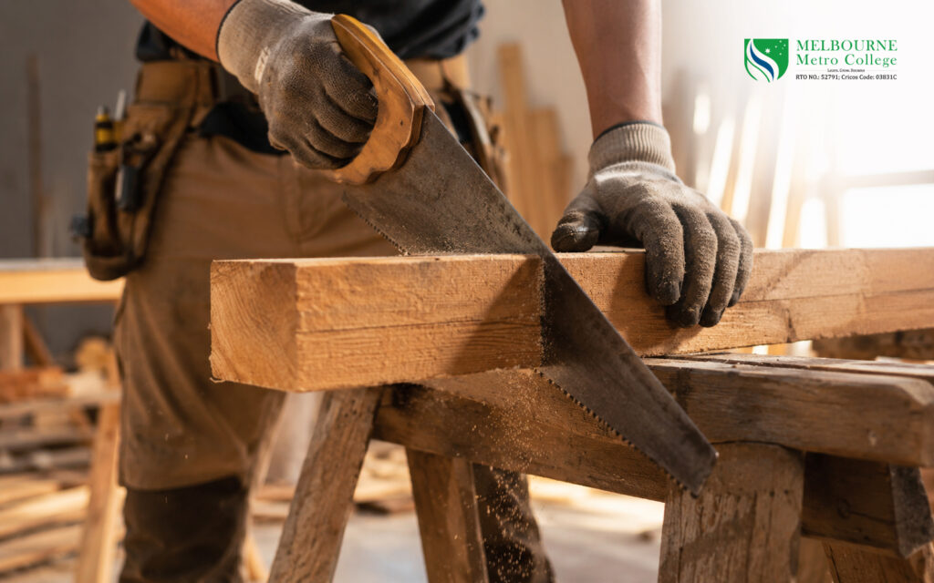 Close-up of hands using a hand saw to cut timber during carpentry skills training